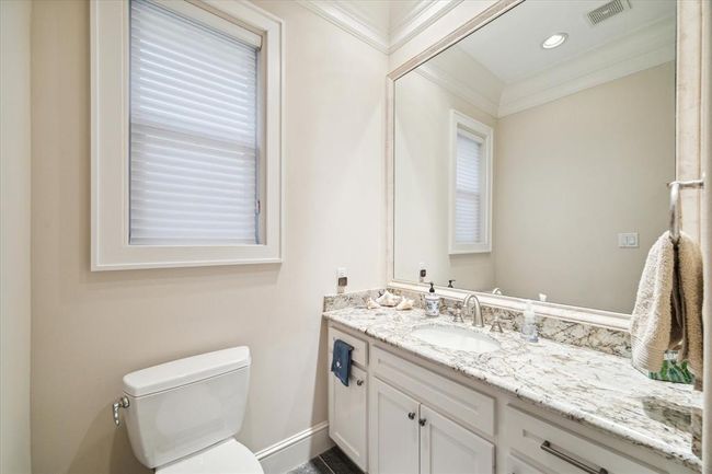 This bathroom features a large vanity with a granite countertop, an under-mount sink, and ample cabinet space. The room is well-lit, with neutral walls and a window for natural light. | Image 28
