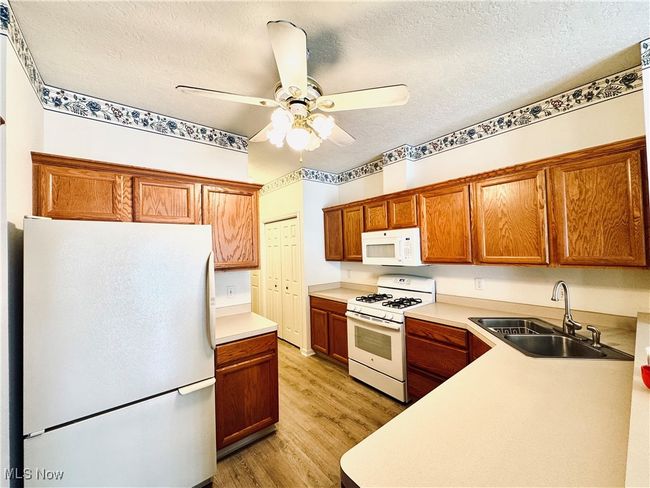 Kitchen featuring a sink, light wood-style floors, white appliances, a ceiling fan, and light countertops | Image 5