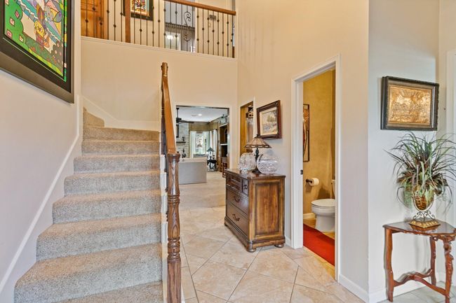 Grand two-story foyer makes a stunning first impression with soaring ceilings and wrought iron ballisters as the centerpiece. The open design allows natural light to flow throughout the space, welcoming guests into this beautiful home with style and grandeur. | Image 5