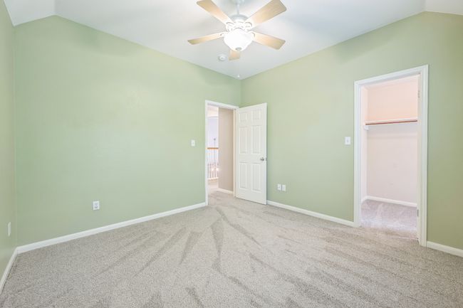 Unfurnished bedroom featuring a walk in closet, ceiling fan, baseboards, lofted ceiling, and carpet flooring | Image 24