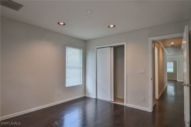 Unfurnished bedroom with dark wood-type flooring, recessed lighting, baseboards, a closet, and attic access | Image 30