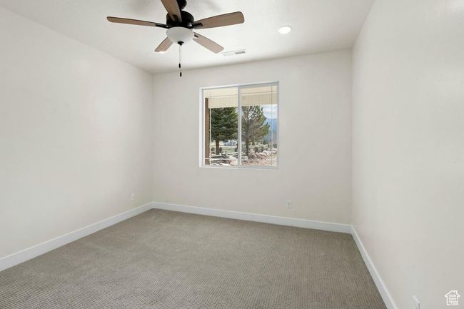 Empty room with light colored carpet, baseboards, a ceiling fan, and visible vents | Image 19