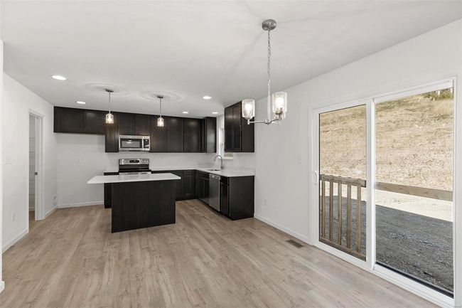 Kitchen with appliances with stainless steel finishes, hanging light fixtures, light hardwood / wood-style floors, and a kitchen island | Image 17