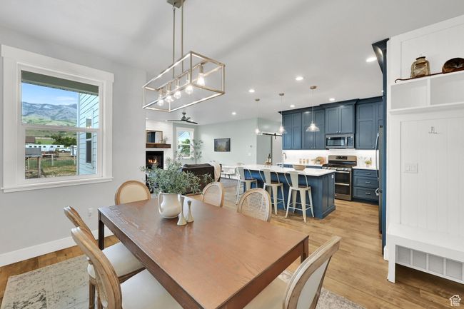 Dining room with a chandelier, light wood-style flooring, a warm lit fireplace, and recessed lighting | Image 14