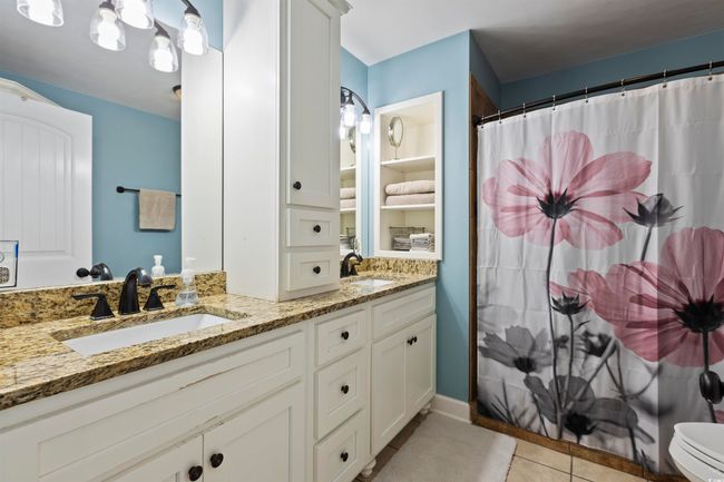 Bathroom with tile patterned flooring, double vanity, curtained shower, and toilet | Image 15