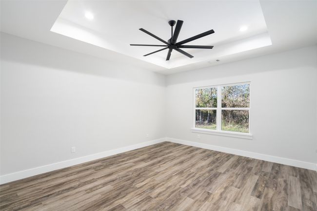 Empty room featuring hardwood / wood-style floors, ceiling fan, and a tray ceiling | Image 19