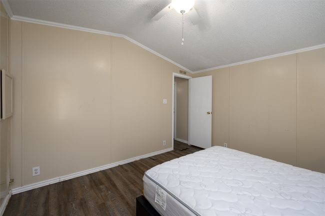 Bedroom with dark wood finished floors, vaulted ceiling, a textured ceiling, ceiling fan, and ornamental molding | Image 19