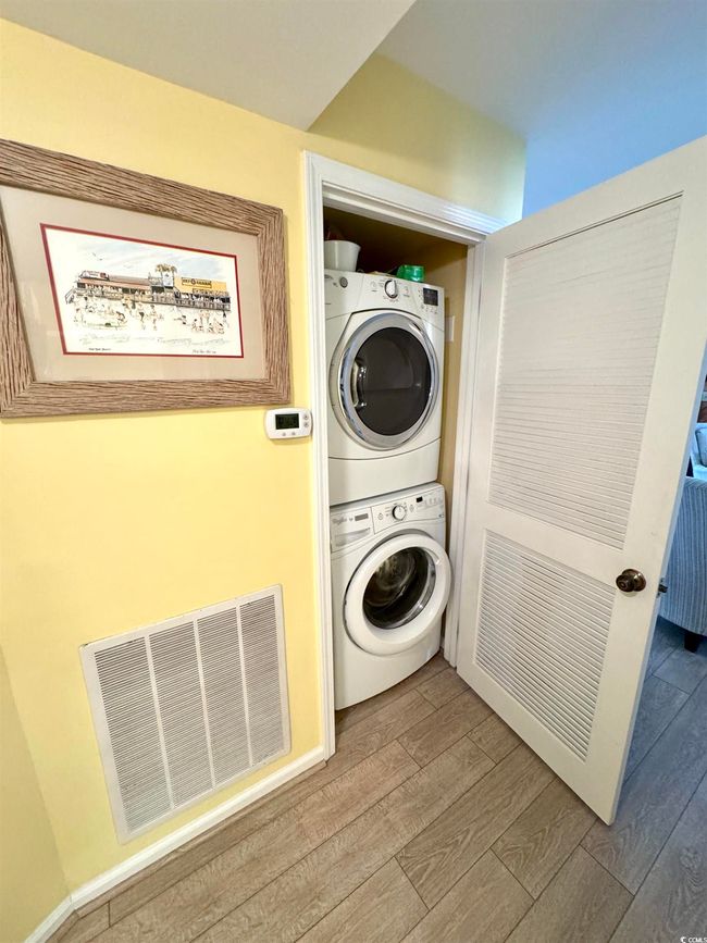 Washroom featuring stacked washing machine and dryer and wood finished floors | Image 23