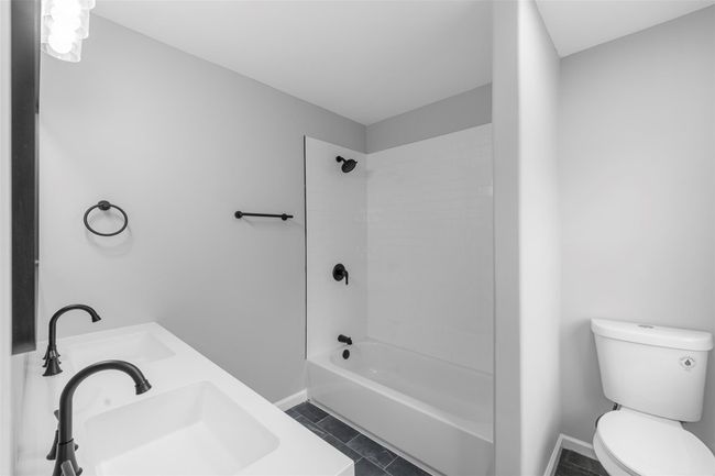 Bathroom featuring baseboards, toilet, double sink, shower / bath combination, and tile patterned flooring | Image 23