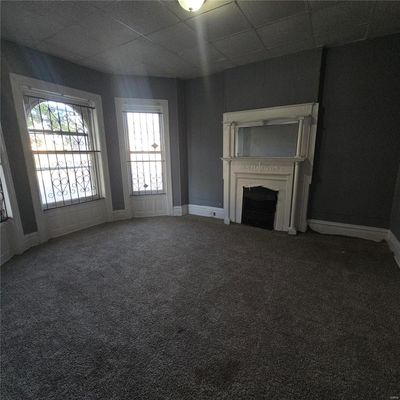 Unfurnished living room featuring a drop ceiling and carpet | Image 3