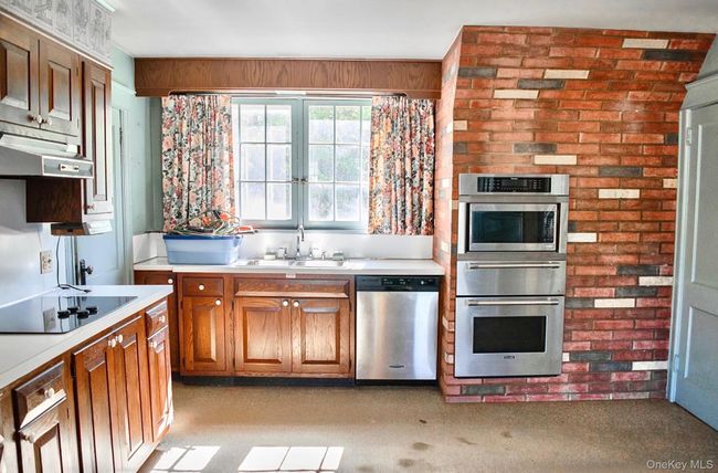 Kitchen with appliances with stainless steel finishes, a sink, light countertops, and a warming drawer | Image 7