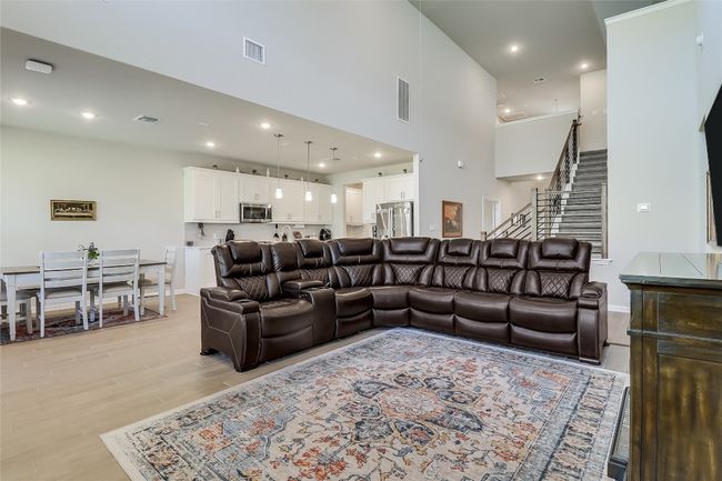 Living area with light wood-style floors, stairway, a towering ceiling, recessed lighting, and baseboards | Image 8