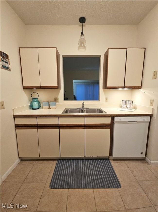 Kitchen featuring a textured ceiling, dishwasher, sink, and hanging light fixtures | Image 8