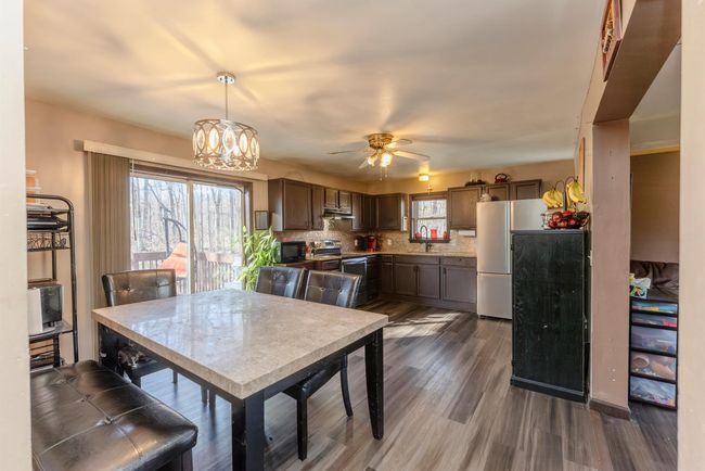 Dining area featuring ceiling fan with notable chandelier and dark wood-style flooring | Image 7