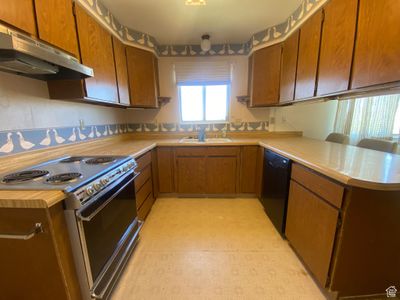 Kitchen with kitchen peninsula, electric stove, dishwasher, light tile flooring, and sink | Image 3