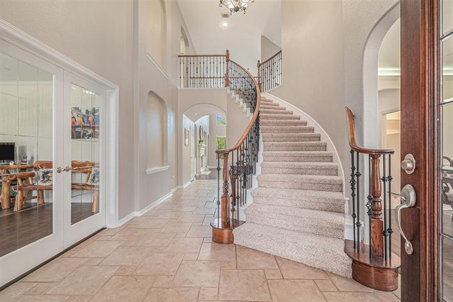 Open the door to an eye-catching staircase that leads to the upstairs living spaces, or you can venture right to the formal dining room, or to the left, tucked behind double glass doors into the home office! | Image 4