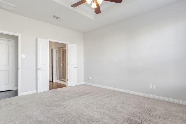 Unfurnished bedroom featuring carpet, a ceiling fan, a tray ceiling, and ornamental molding | Image 19