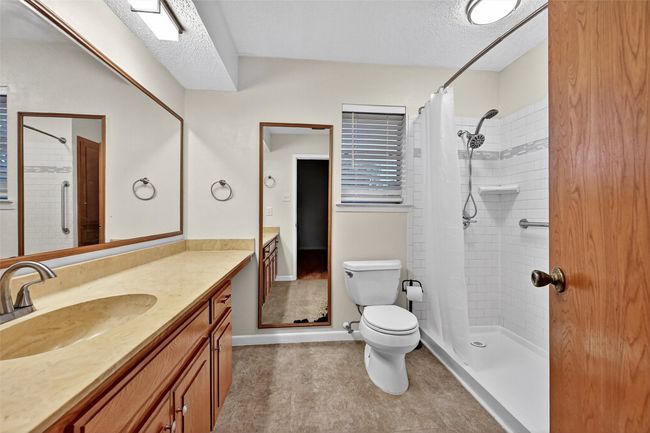 Bathroom featuring vanity, a tile shower, and a textured ceiling | Image 13