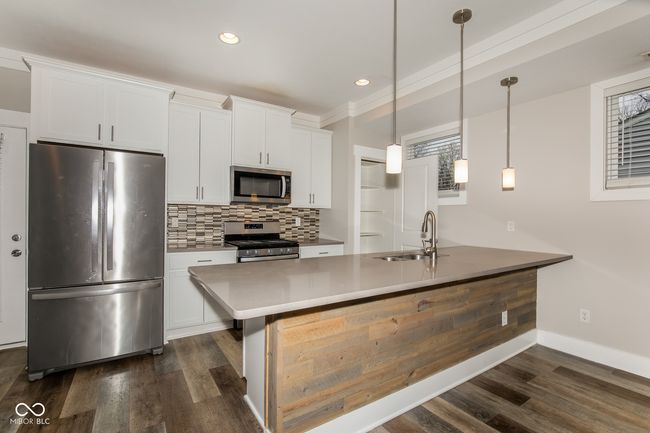 kitchen with stainless steel appliances, a sink, backsplash, and dark wood finished floors | Image 15