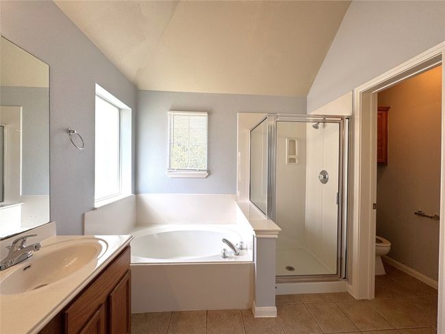 Bathroom featuring lofted ceiling, a bath, a shower stall, vanity, and tile patterned floors | Image 10