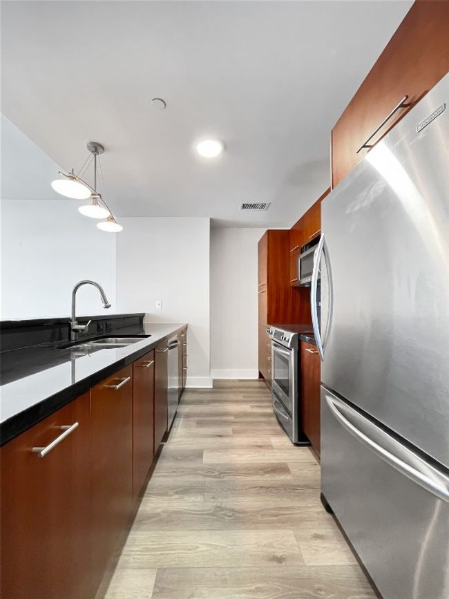 Kitchen featuring stainless steel appliances, modern cabinets, a sink, dark countertops, and recessed lighting | Image 10