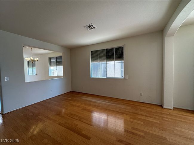 Empty room with healthy amount of natural light, a chandelier, and wood finished floors | Image 5