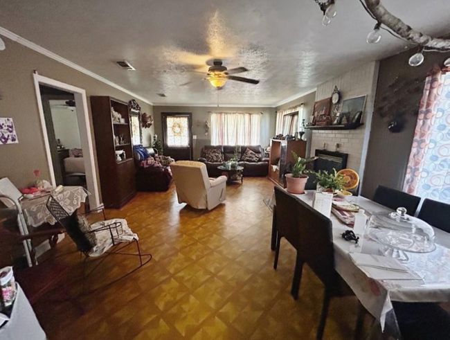 Dining area with visible vents, a brick fireplace, crown molding, and a ceiling fan | Image 5