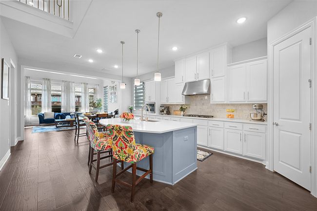 Kitchen featuring decorative backsplash, gas stovetop, light countertops, under cabinet range hood, and dark wood-style floors | Image 10