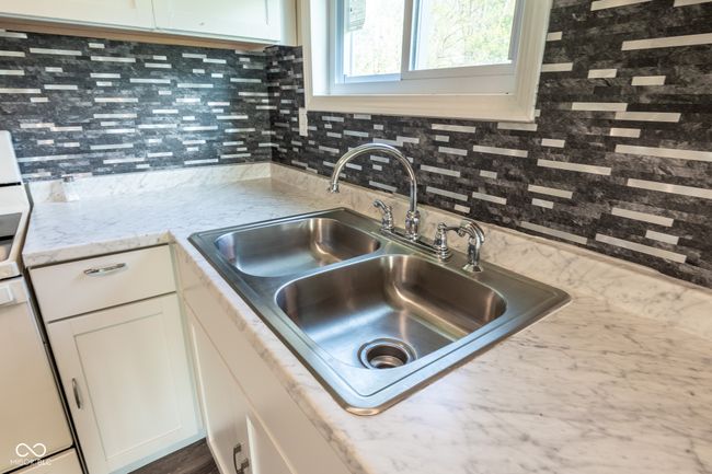 kitchen featuring a sink, backsplash, white cabinetry, and range | Image 16