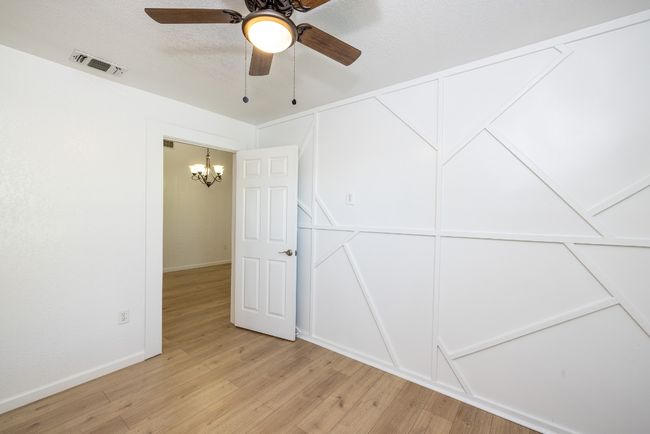 Empty room featuring light wood-type flooring, ceiling fan with notable chandelier, baseboards, and visible vents | Image 20