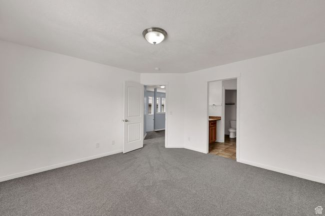 Unfurnished bedroom with dark carpet, a textured ceiling, and ensuite bathroom | Image 20