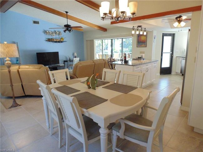 Dining area with plenty of natural light, light tile patterned flooring, visible vents, and ceiling fan with notable chandelier | Image 10