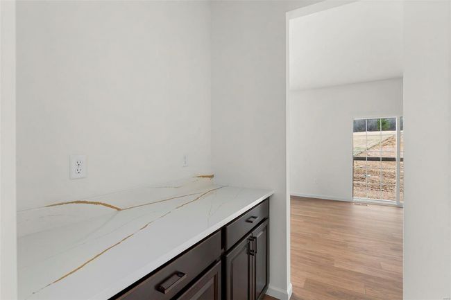 Bar with light stone countertops, dark brown cabinets, and light hardwood / wood-style floors | Image 25