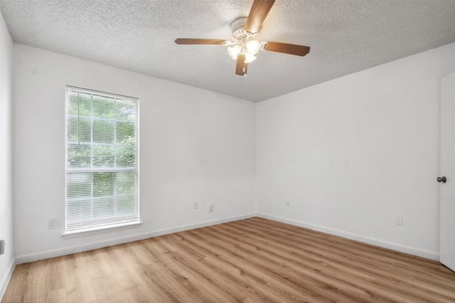 Empty room featuring light wood-style floors, baseboards, ceiling fan, and a textured ceiling | Image 11