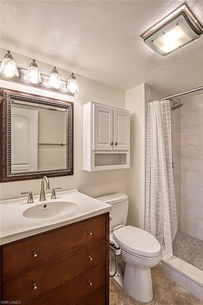 Bathroom with a textured ceiling, a stall shower, toilet, tile patterned floors, and vanity | Image 31