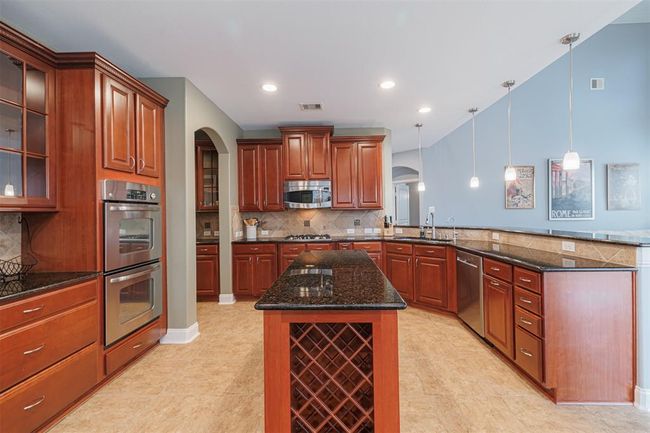 The open-concept kitchen offers an island w/wine rack, recessed and pendant lighting, stainless steel appliances and breakfast bar. | Image 14