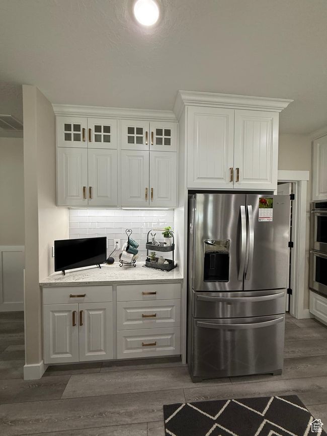 Kitchen with dark wood finished floors, white cabinetry, tasteful backsplash, and appliances with stainless steel finishes | Image 26