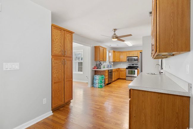 Kitchen with appliances with stainless steel finishes, a sink, ceiling fan, light countertops, and baseboards | Image 26