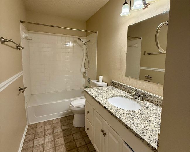Bathroom with vanity, toilet, shower / bath combination, a textured ceiling, and baseboards | Image 10