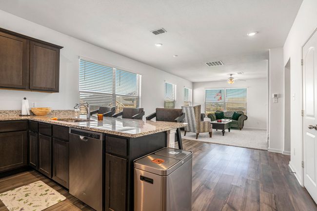 Kitchen with a sink, dishwasher, a peninsula, vinyl plank floors, and dark brown cabinets | Image 11