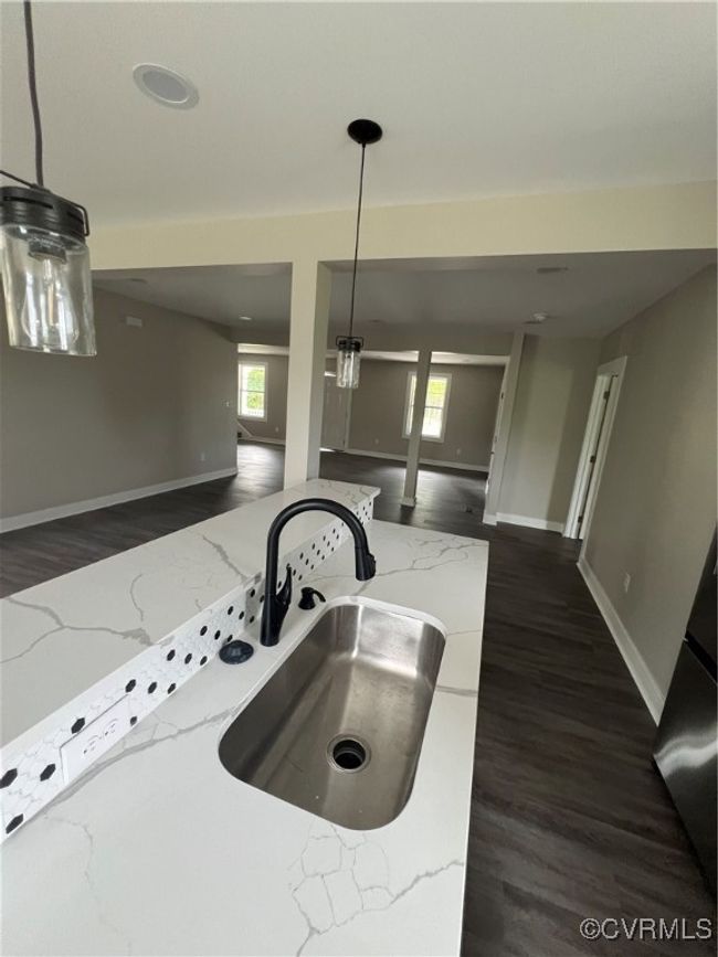 Kitchen with baseboards, light stone counters, dark wood finished floors, a sink, and open floor plan | Image 8