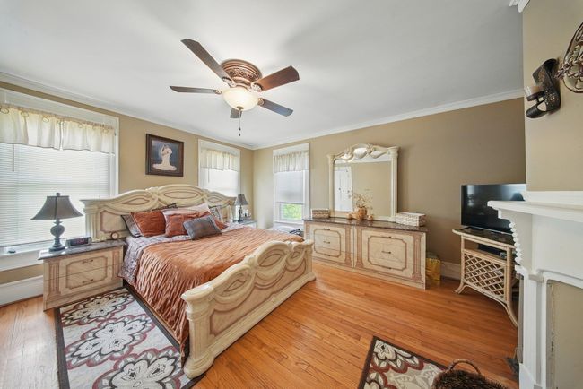 Bedroom with ornamental molding, light wood-style floors, and a ceiling fan | Image 21