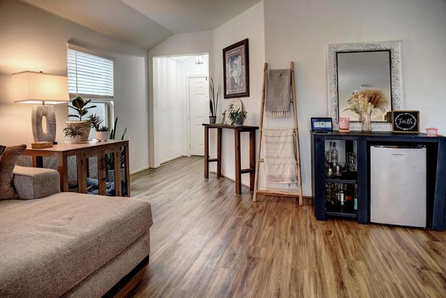 Bedroom featuring lofted ceiling, baseboards, wood finished floors, and refrigerator | Image 6