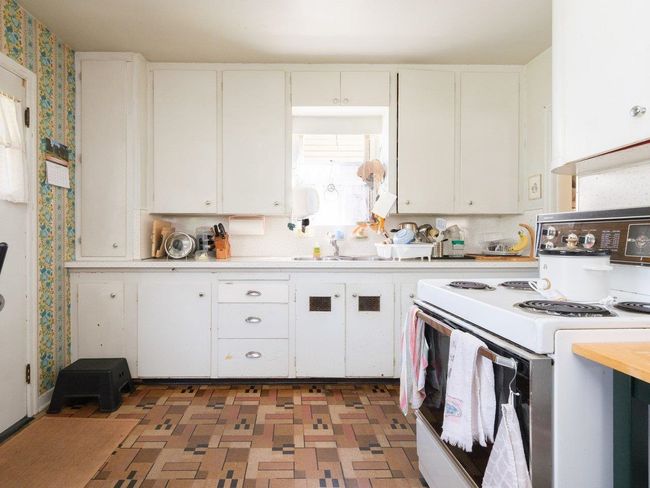 Kitchen featuring white range with electric cooktop, light countertops, wallpapered walls, and white cabinets | Image 11