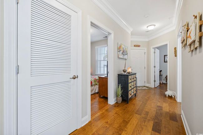 Corridor with wood-type flooring, crown molding, and baseboards | Image 23
