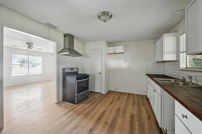 Kitchen with wall chimney range hood, gas range, a sink, wooden counters, and light wood finished floors | Image 19