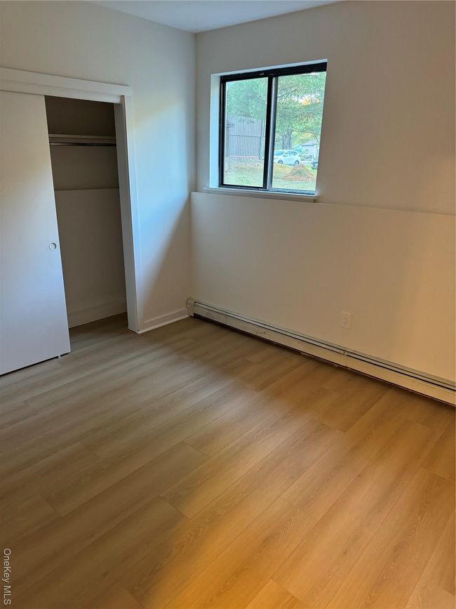 Unfurnished bedroom with a baseboard heating unit, light wood-type flooring, and a closet | Image 5