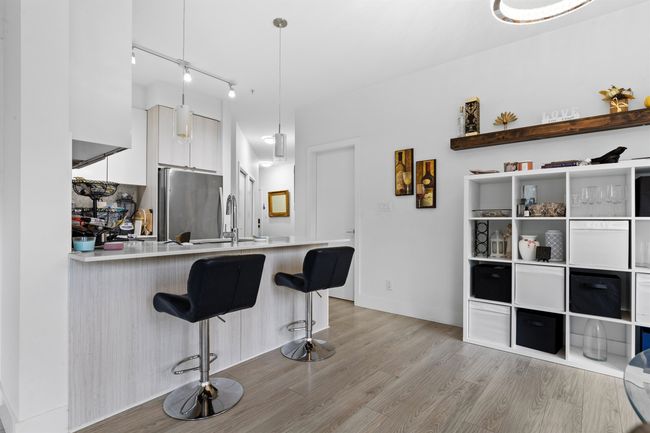 Kitchen featuring freestanding refrigerator, white cabinetry, light wood finished floors, and a peninsula | Image 13
