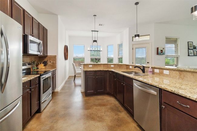 Kitchen featuring appliances with stainless steel finishes, concrete flooring, backsplash, and healthy amount of natural light | Image 13