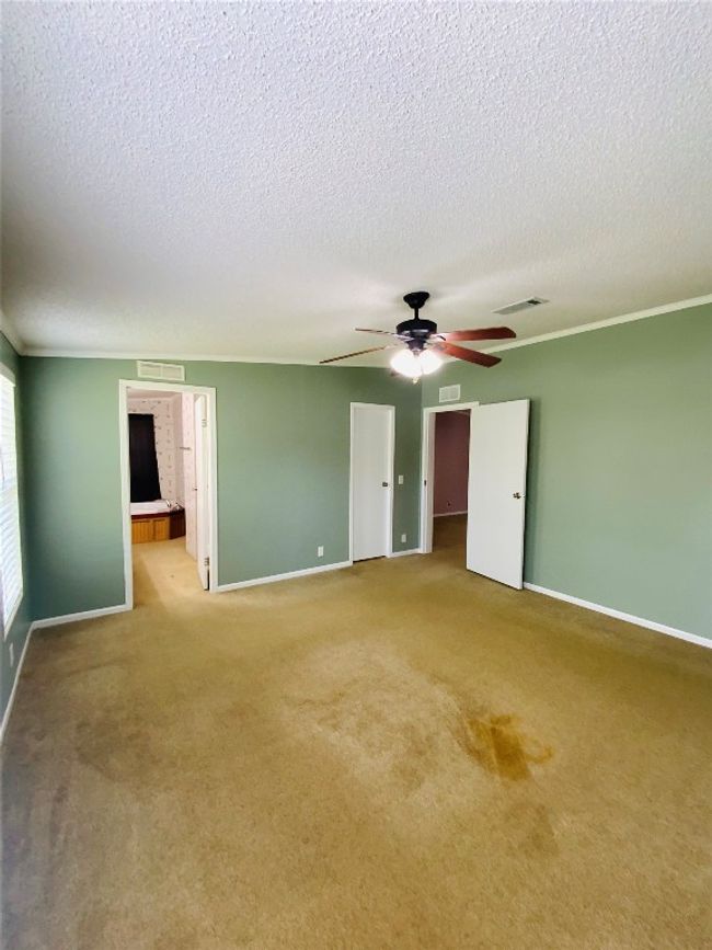 Carpeted empty room featuring baseboards, a ceiling fan, visible vents, and a textured ceiling | Image 17